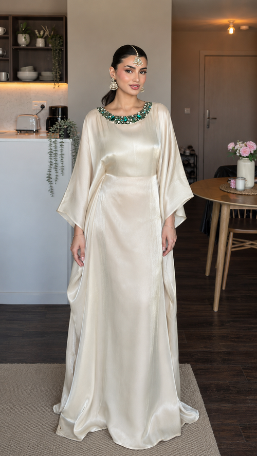 Front view of champagne satin-look maxi dress with green embellished neckline and flowing kaftan sleeves