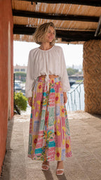 Front view of model wearing white crop top and pink multi printed maxi skirt