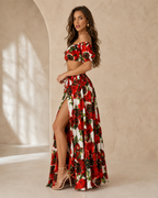 Woman wearing a red floral off shoulder crop top and high slit maxi skirt set front side view