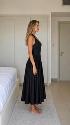 Side view of woman wearing black halter neck midi dress