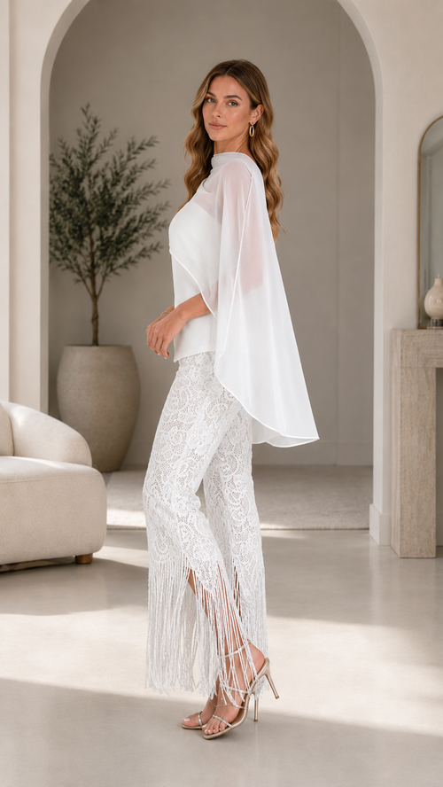 Side view of white formal two-piece set with sheer cape overlay and fringe hem pants