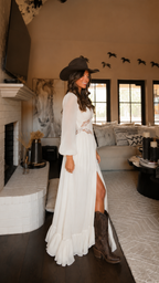 Side view of ivory flowing maxi dress with bishop sleeves, waist trim detail and ruffled hem