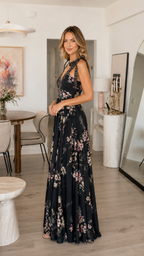 Side view of black floral sleeveless maxi dress with shoulder bows and flowing skirt