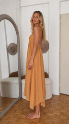 Side profile view of mustard yellow maxi dress with asymmetric hem