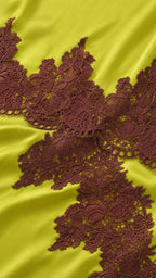 Close-up detail of dark brown lace applique on lime satin fabric