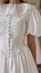 Close up of lace bodice and button details on white dress