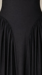 Close-up detail of dropped waist and pleats on black dress