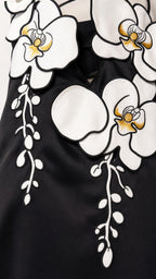 Close-up detail of the 3D white and yellow floral appliques on the black dress bodice
