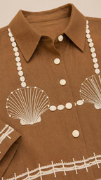 Close-up detail of lapel collar and shell embroidery on brown top