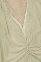 Close-up of V-neckline and lace trim detail in sage green