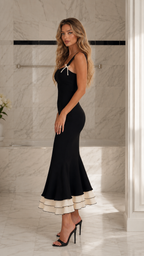 Side view of black fitted mermaid midi dress with flared contrast hem